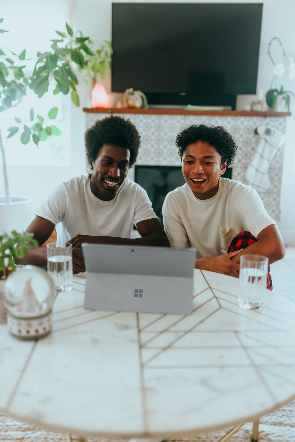 Freunde sitzen im Wohnzimmer vor dem Tablet PC und lächeln in den Videocall  | © surface-VfDX9EXTwEA-unsplash