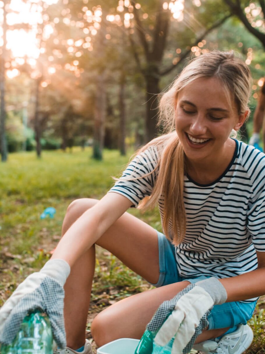 Junge Frau sammelt Plastikflaschen für Recycling ein